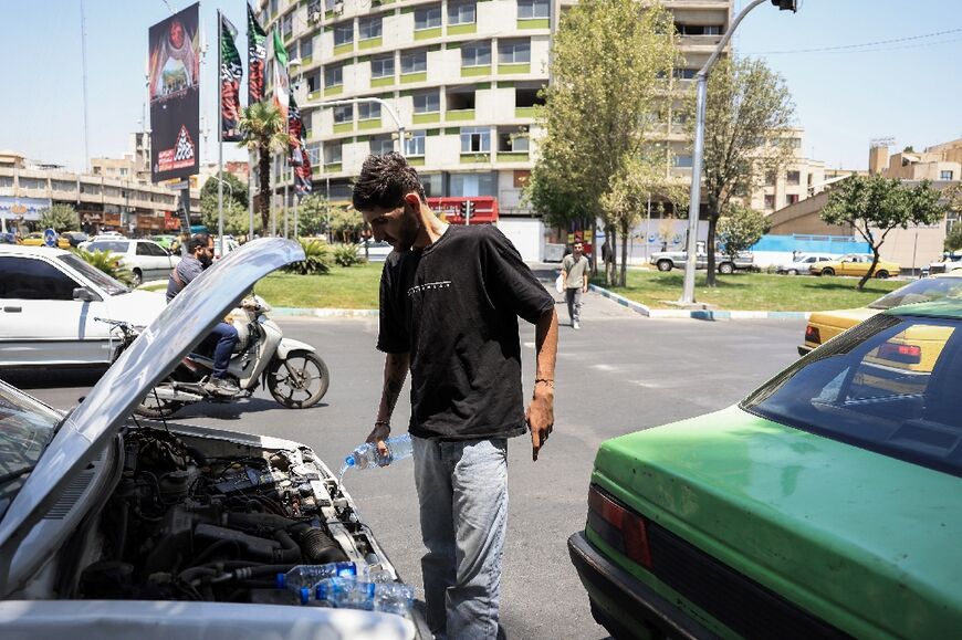 An Iranian taxi driver tries to cool down his engine after his radiator overheated in the soaring temperatures in Tehran.