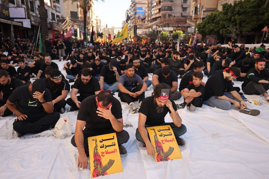 Hezbollah supporters hold a sign that reads: "We will not relinquish arms"