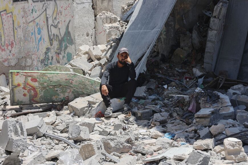 A Palestinian man sits amid the rubble of buildings destroyed in Israeli strikes on Gaza City