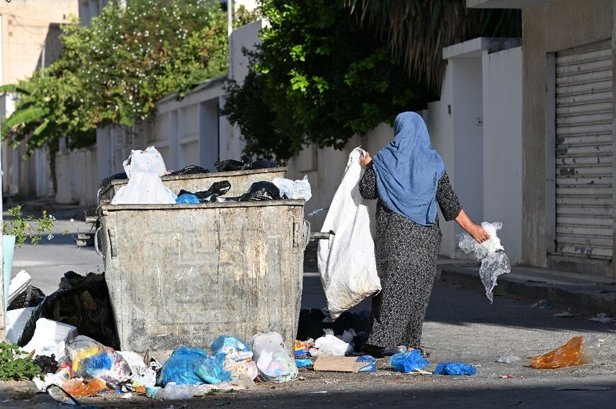 A woman rummages through a garbage bin to salvage plastic in the Ariana region near Tunis