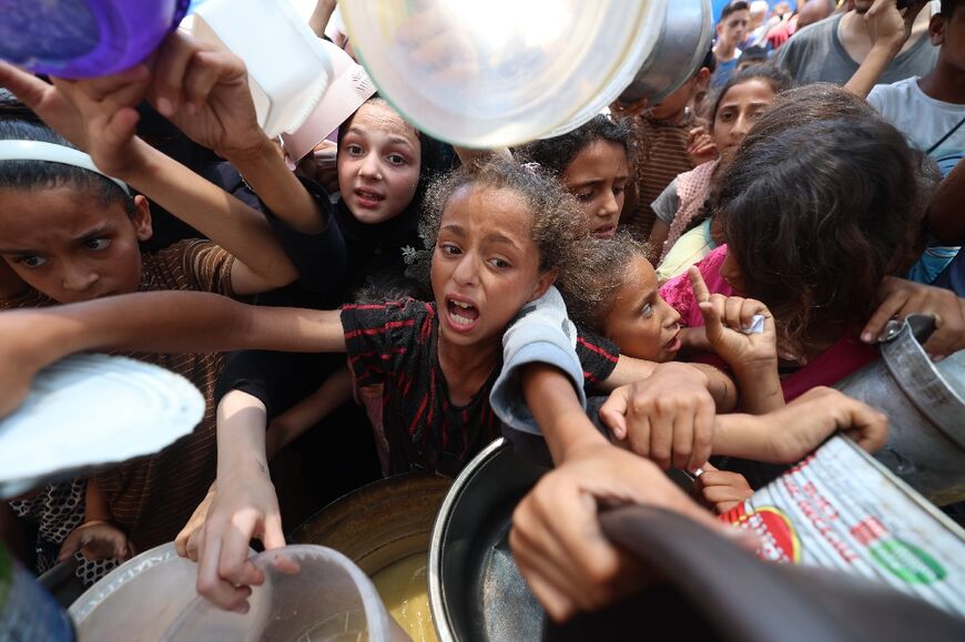Palestinian children crowded round to receive a hot meal at a food distribution point in Nuseirat on June 30
