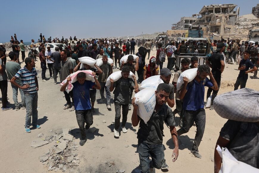 People make their way along al-Rashid street in western Jabalia on July 22, 2025, after receiving humanitarian aid from an aid distribution point in the northern Gaza Strip