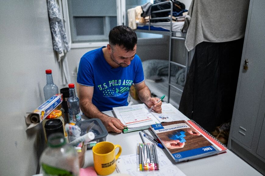Kurd Faruk Polat, 34, works on his German in his overcrowded shelter in Berlin's former Tempelhof airport 
