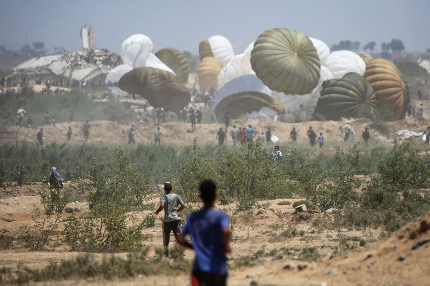 Palestinians rush to the site where parachuted aid packages are landing in the Nuseirat area in the central Gaza Strip
