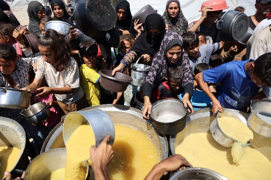 Palestinians receive rations of lentil soup at a food distribution point in Gaza City.