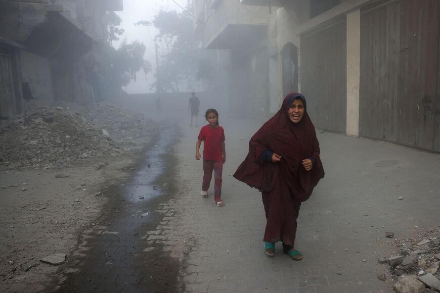 A Palestinian woman and children run from Israeli air strikes in the Saftawi neighborhood of the northern Gaza Strip 