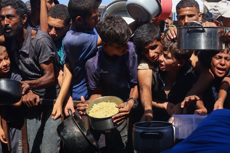 Palestinians receive food portions from a charity kitchen in the southern Gaza Strip, amid fears of famine spreading across the territory