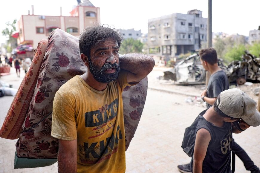 A Palestinian man carries a mattress as he flees a Gaza City neighbourhood following Israeli bombardment