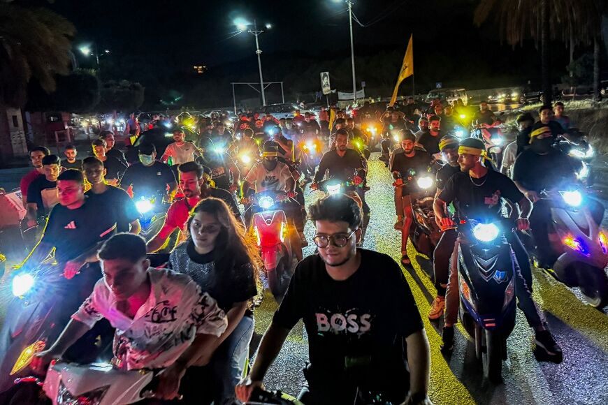 Supporters of Lebanon's Hezbollah militant group lift flags as they rally in cars and motorbikes in Beiruit to protest the government's endorsement of a plan to disarm it