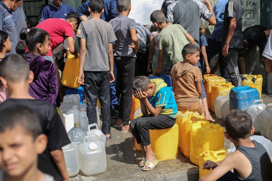 Palestinian queue for water at a distribution point in central Gaza's Nuseirat refugee camp