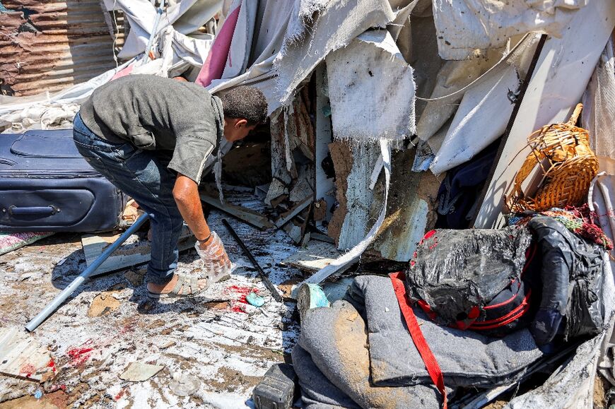 People inspect damage at a tent encampment hit by Israeli bombardment, in Gaza City