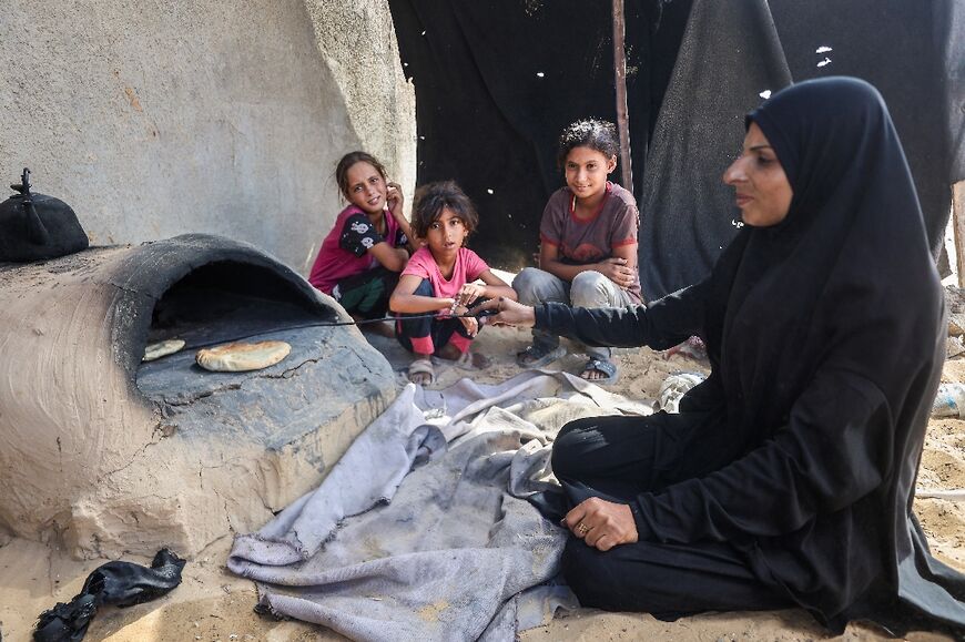 A Palestinian woman makes bread at a makeshift displacement camp in a cemetary in Khan Yunis, in southern Gaza