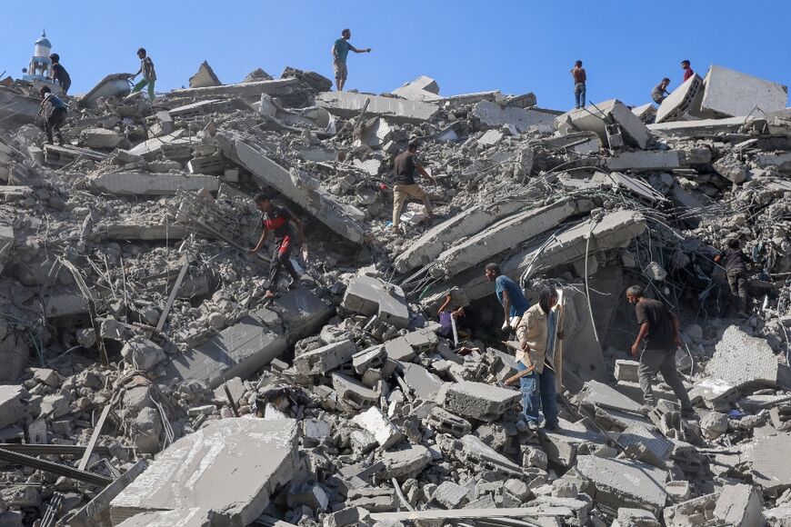 Palestinians search the rubble of al-Ghafari tower after its destruction by Israeli air strikes in Gaza City on Monday