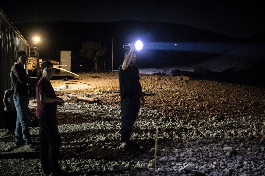 A Palestinian Bedouin man shines a torchlight as he searches for any approaching settlers in Ras Ein al-Auja, in the Jordan Valley in the Israeli-occupied West Bank