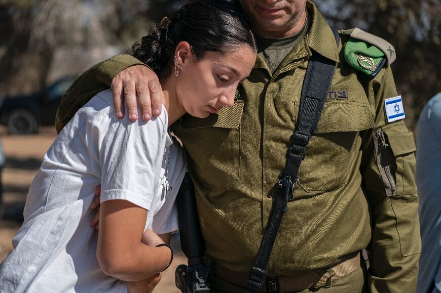 An Israeli soldier comforts a woman during the memorial ceremony at Kfar Aza