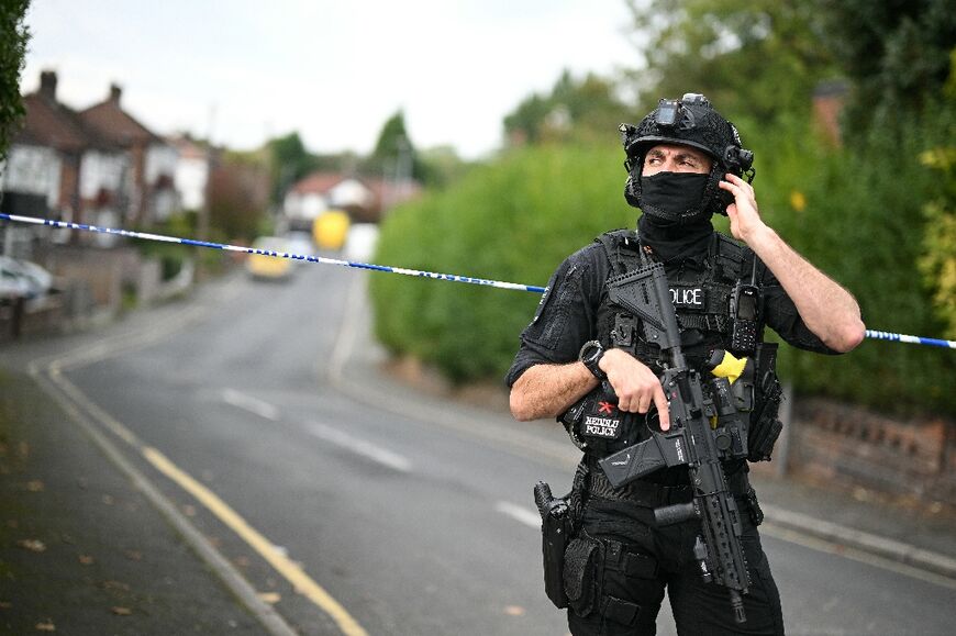 An armed police officer stands at a cordon patrolling the area around the Manchester synagogue
