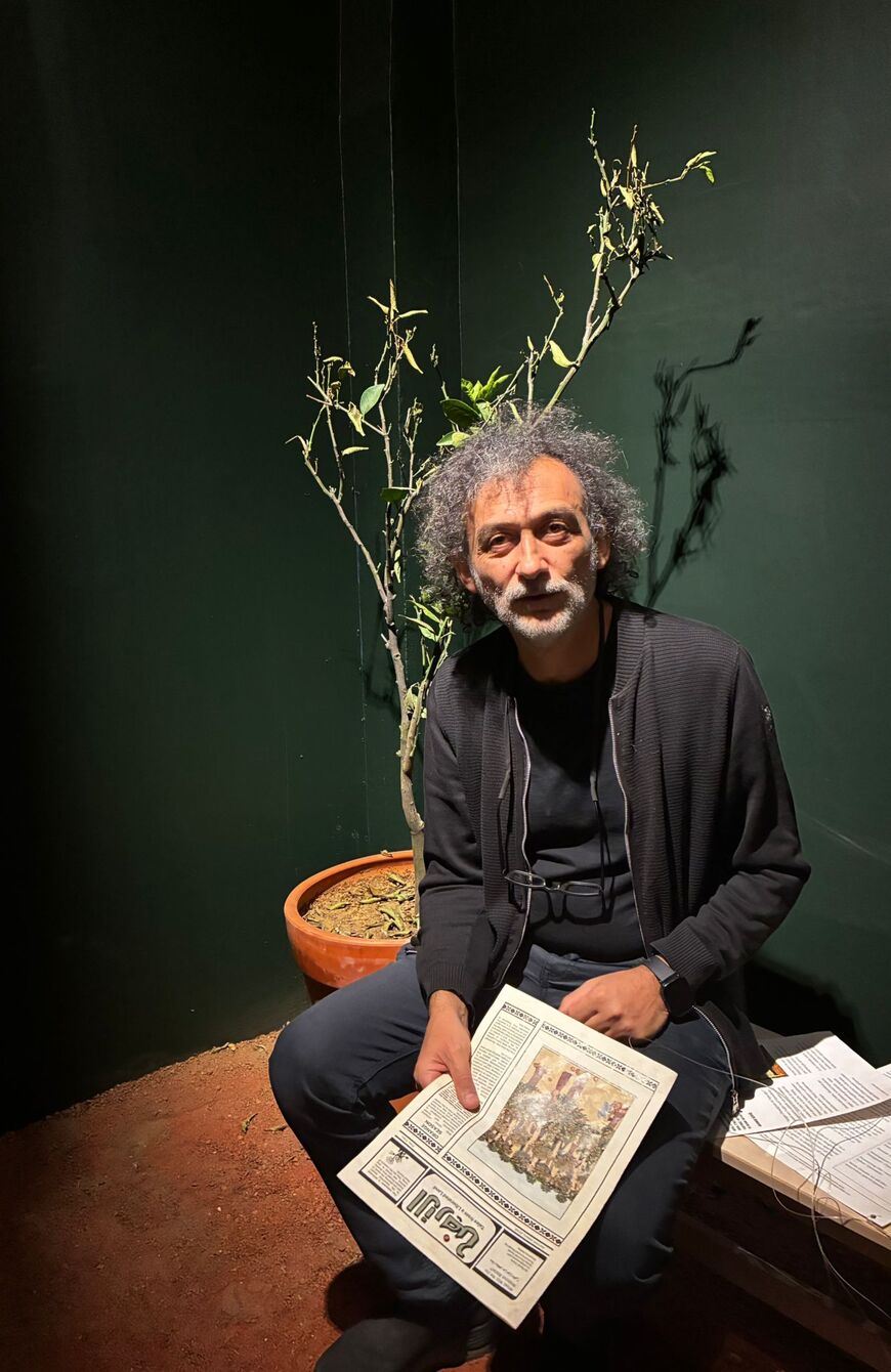 Kubilay Ozmen, one of the co-curators, in Basel Zaraa’s work, “What Will We Do Without Exile?” which consists of a tent with flower pots of olive and lemon trees.  (Photo: Nazlan Ertan)