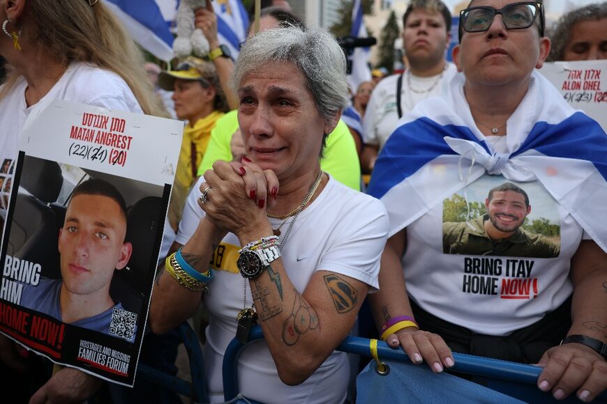 Des Israéliens brandissant des portraits d’otages israéliens encore retenus à Gaza attendent leur libération sur la place des Otages à Tel-Aviv, tôt le 13 octobre 2025