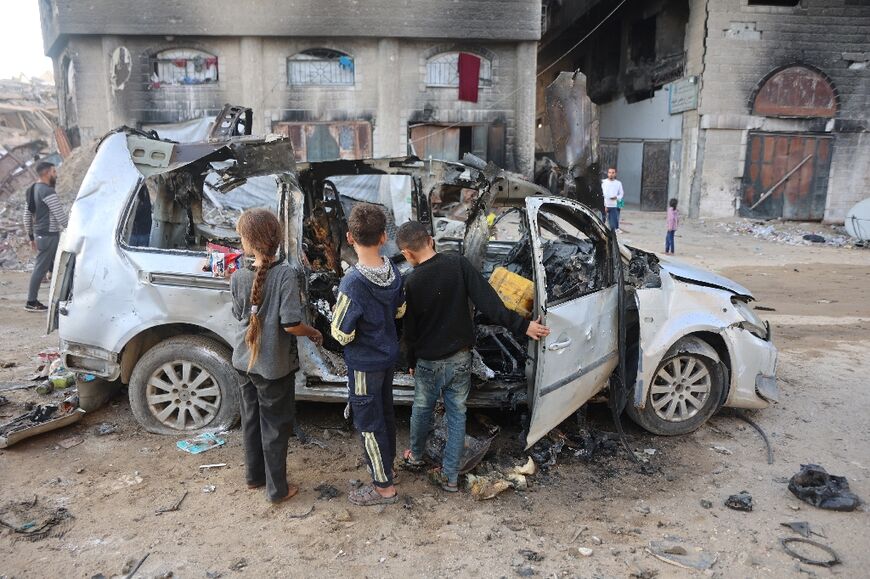 Palestinian children look at a destroyed vehicle in Gaza City