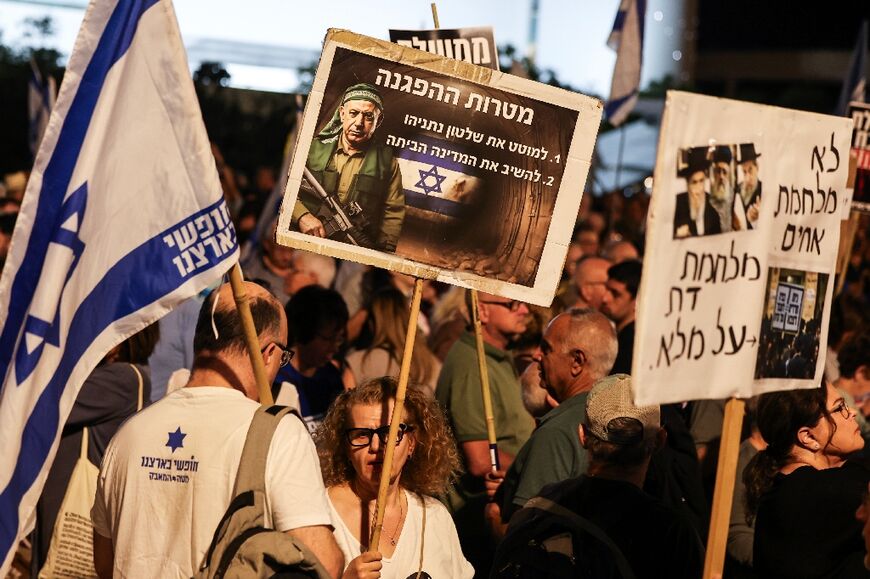 A demonstrator holds a placard reading in Hebrew: 'Goals of the protest: To topple Netanyahu's rule and to return the country to the nation'