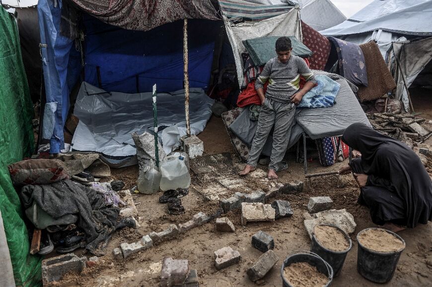 A Palestinian woman fixes her makeshift shelter at a displacement camp in Gaza City