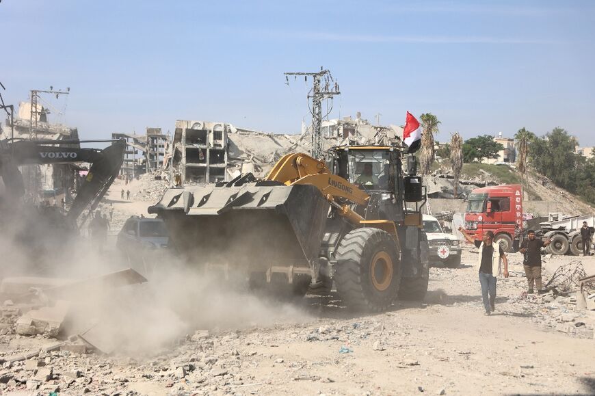 A digger supplied by Egypt moves the rubble of destroyed buildings during the search for the bodies of dead Israeli hostages
