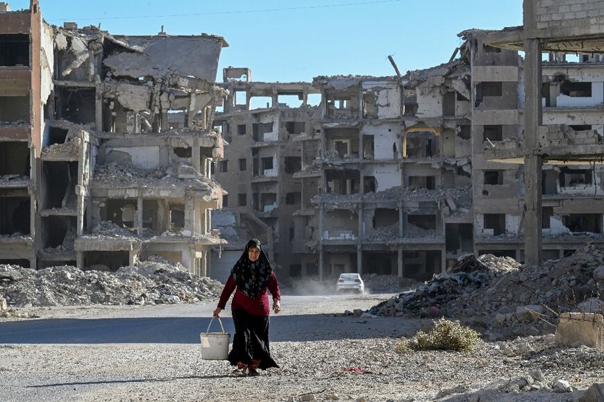 Undimmed spirit: a woman carries a bucket from her home in the devastated Syrian city of Daraya
