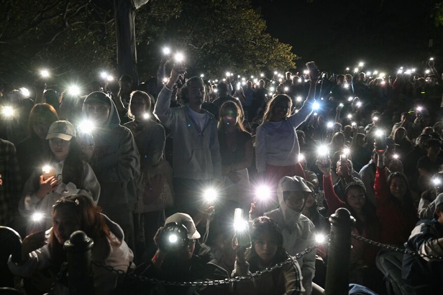 People turn on their mobile phones' flashlights  to observe a minute's silence to reflect on the tragic Bondi Beach shooting attack before the New Year's Eve midnight fireworks display in Sydney 