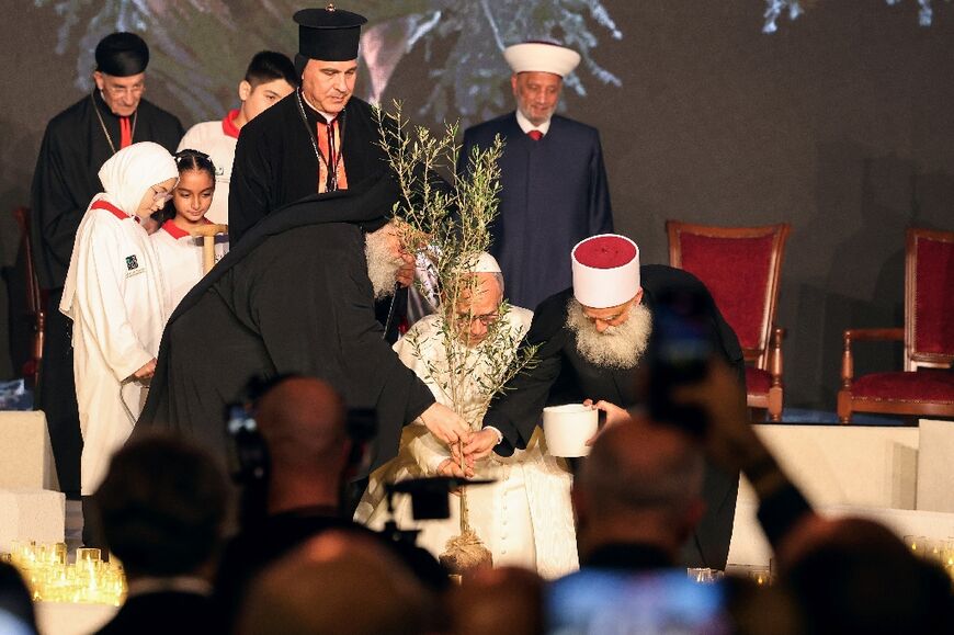 Pope Leo (C) plants an olive tree alongside other religious leaders during Monday's interfaith meeting