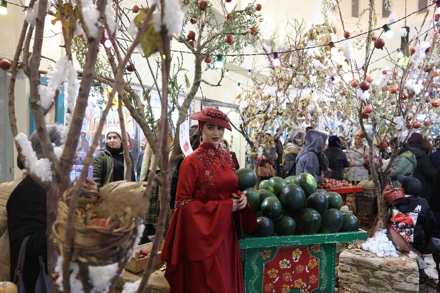 An Iranian woman in traditional dress amid Yalda decorations in northern Tehran