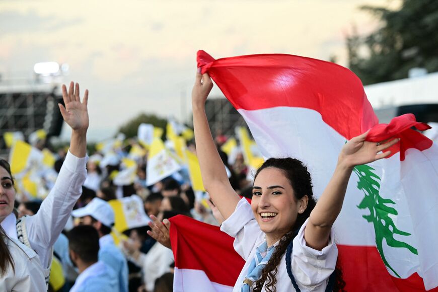 A woman waves a Lebanese flag as she waits for the Pope during a meetin with youths at the Maronite Patriarchate in Bkerke, north of the capital Beirut, on December 1, 2025. Pope Leo XIV prayed for peace in Lebanon and the region on December 1 on day two of his trip to the multi-confessional country, with joyful Lebanese welcoming the pontiff at two famous pilgrimage sites. (Photo by Giuseppe CACACE / AFP via Getty Images)