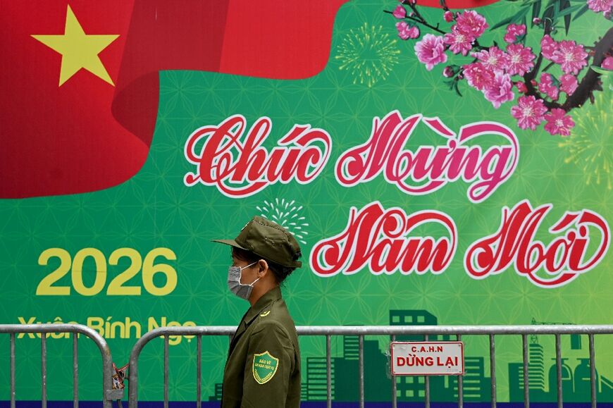 A security guard walks past a New Year's greeting banner in Hanoi