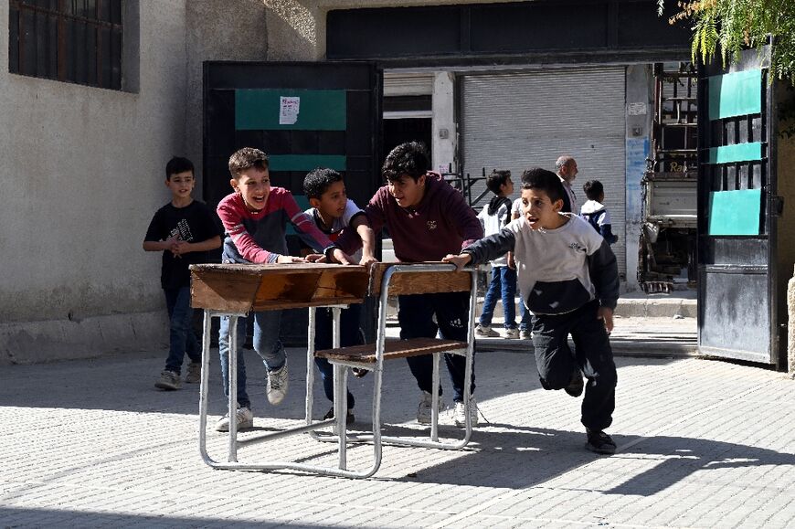Children help move desks back into their school in Daraya