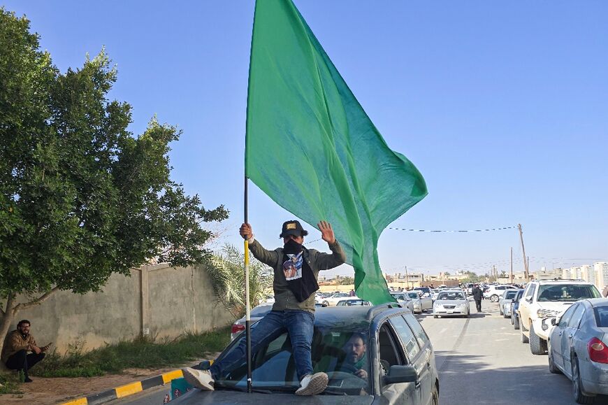 A Libyan holds up the green flag, used by loyalists of the former ousted leader Muammar Gaddafi, as people gather for the funeral of Seif al-Islam Gaddafi, the son of the late ruler, in the town of Bani Walid