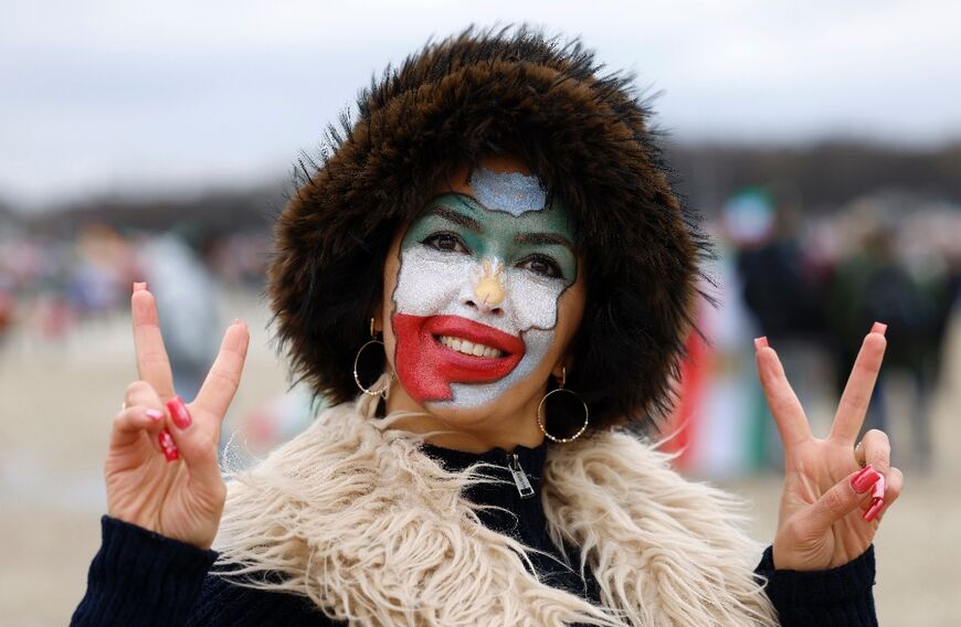 A woman made up in the colors of Iran flashes the victory sign as she arrives for the demonstration 