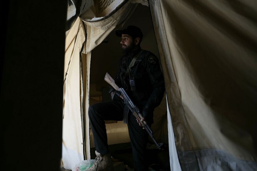 A Syrian soldier stands guard in a tent at the Al-Hol camp
