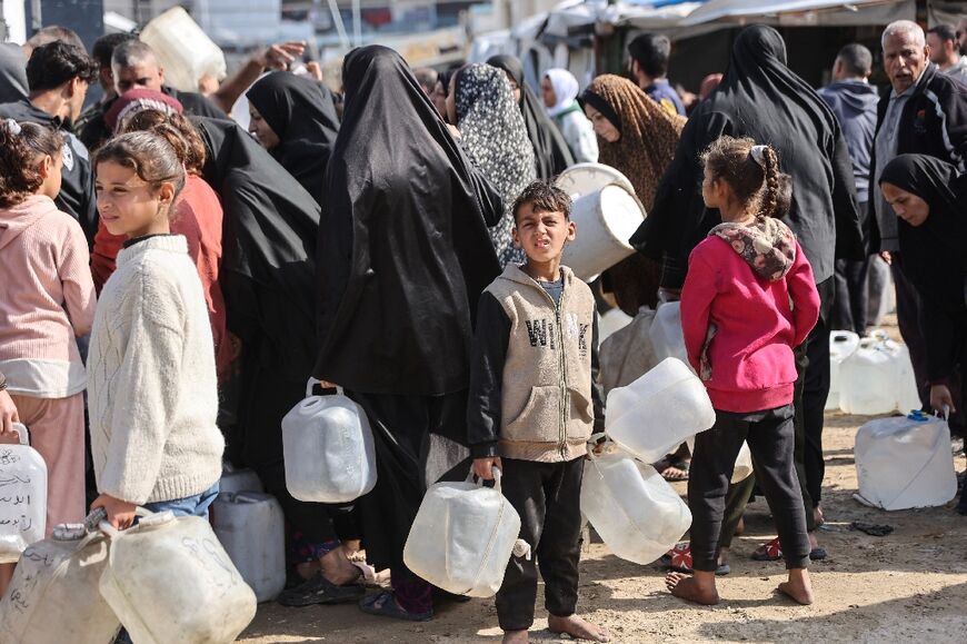 Displaced Palestinians wait for food and water aid in Gaza amid an ongoing ceasefire