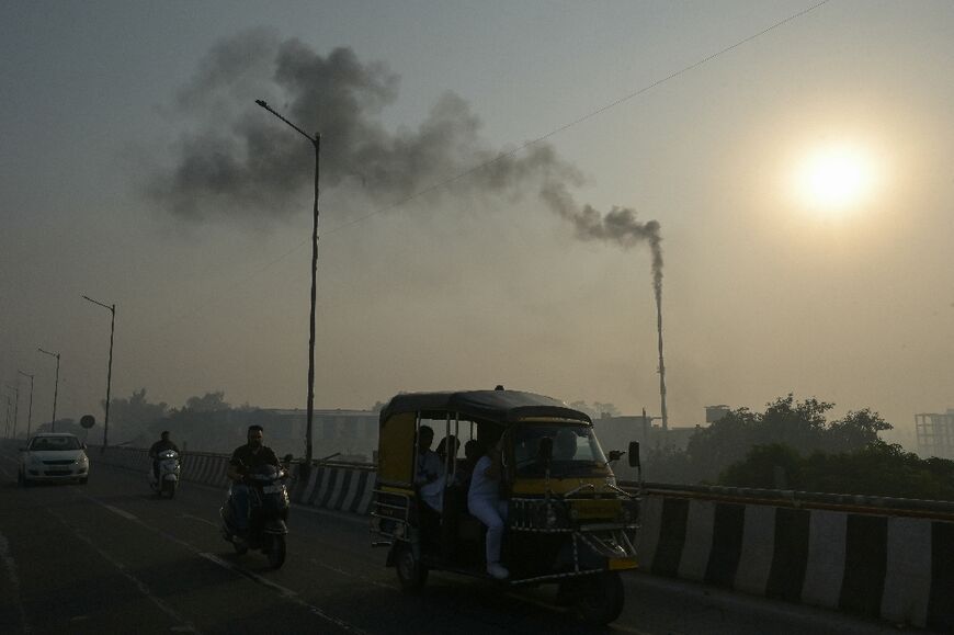 Smoke billowing from a factory chimney as commuters make their way through smoggy conditions in Amritsar, India