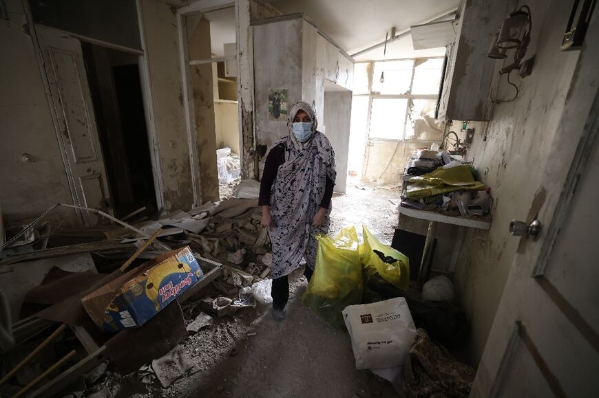 An Iranian woman collects belongings from her destroyed home following a military strike on Tehran on March 15
