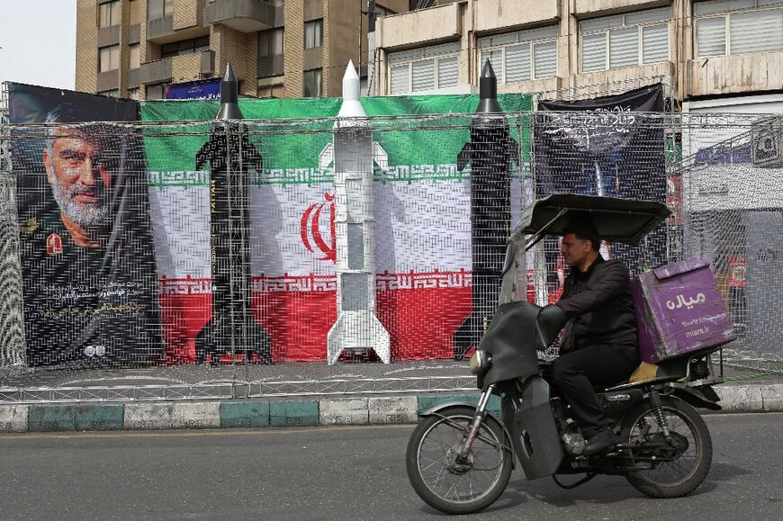 A motorist drives past mock Iranian missiles displayed in Tehran's Valiasr square on March 22