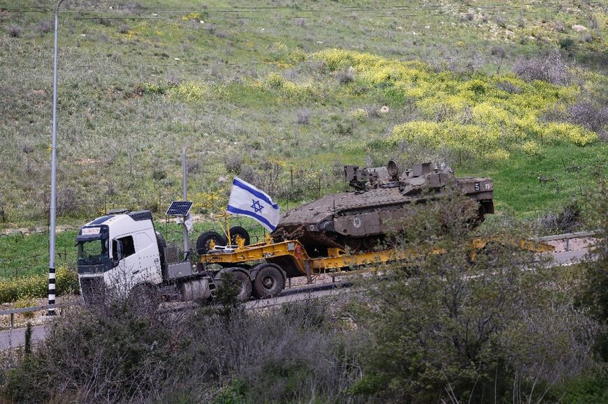 An Israeli military truck carries a tank in the Upper Galilee region of northern Israel, near the border with Lebanon