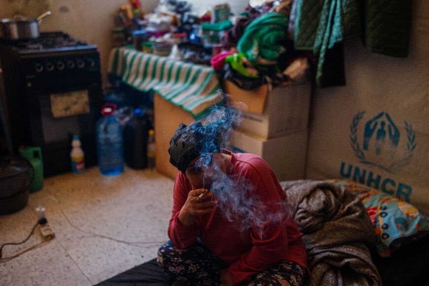 A displaced woman smokes a cigarette in a room at a school serving as a shelter for displaced people in the southern Lebanese city of Tyre