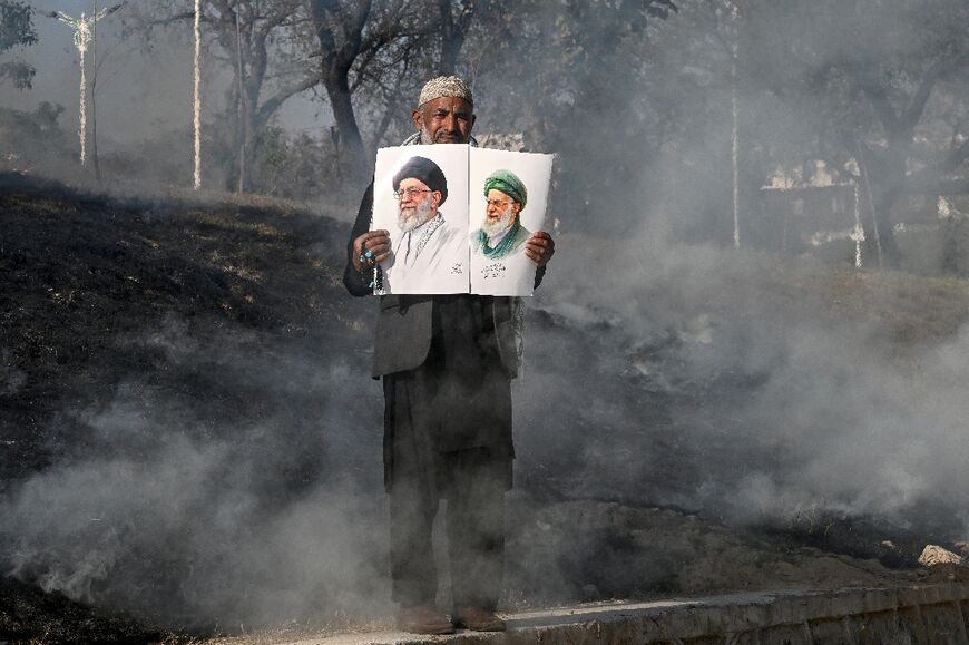 A man holds photos of Iran's late supreme leader Ayatollah Ali Khamenei as protesters attempt to storm the US embassy in Islamabad on March 1, 2026