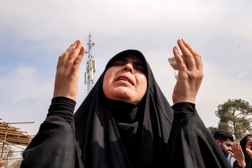 A mourner prays during the burial of a person killed in recent US-Israeli airstrikes at a grave in a cemetery in Tehran 
