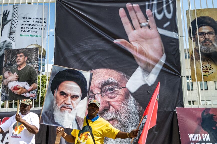 Protesters carry a banner  with a portrait of the late Iranian leader Ayatollah Ali Khamenei (C) in Johannesburg