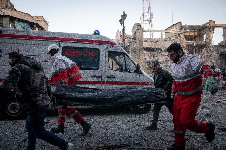 Rescue workers carry the body of a victim after a strike on a building in Tehran's Enghelab Square