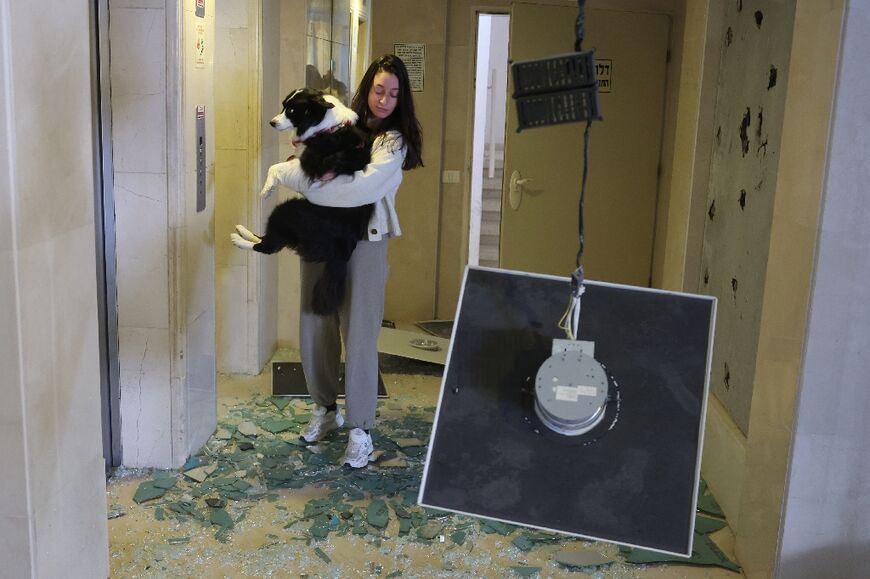 A woman carries her dog in a building damaged in an Iranian missile strike in Tel Aviv