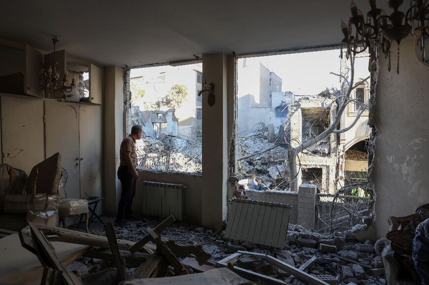 An Iranian resident looks out the window of his damaged home after Israeli-US strikes in Tehran on April 7, 2026