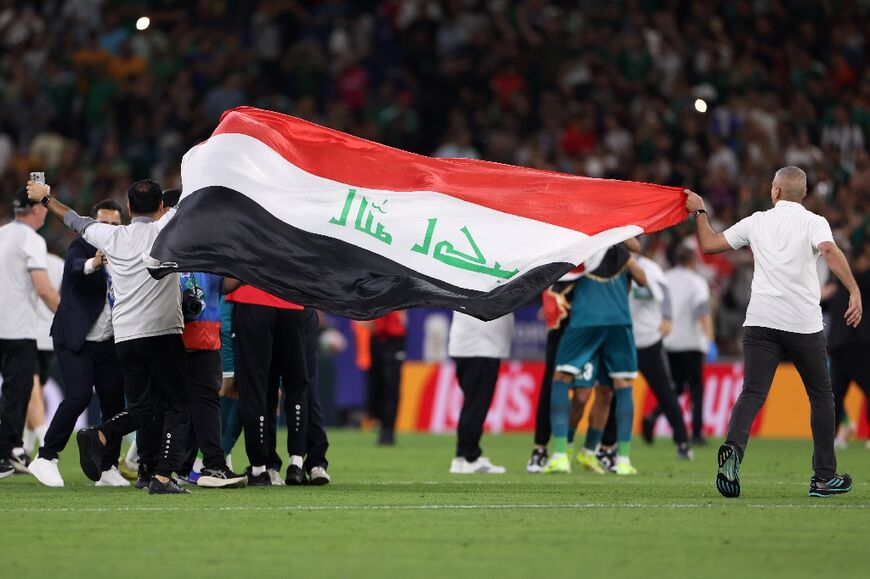 Iraqi staff members wave a national flag after winning the 2026 FIFA World Cup playoff against Bolivia