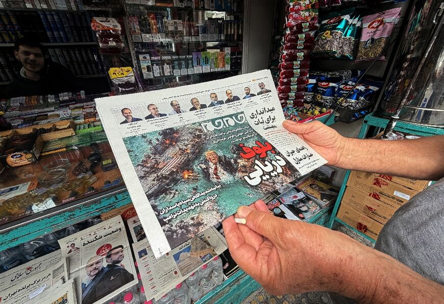 A man looks at the front page of the Jam Jam newspaper on sale at a newsstand in Tehran, featuring a cartoon of US President Donald Trump drowning in the Strait of Hormuz with the headline “Marine Bluff” 